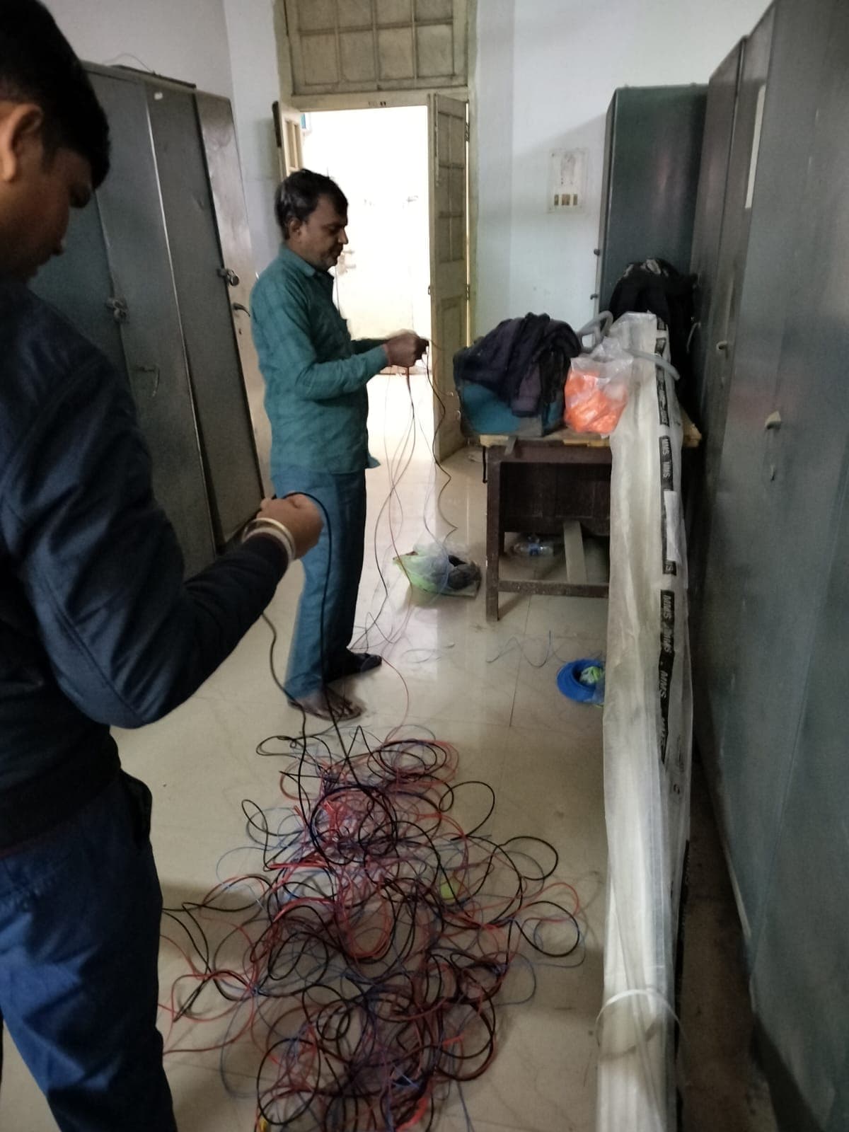 Two electricians measuring and coiling colour-coded wiring