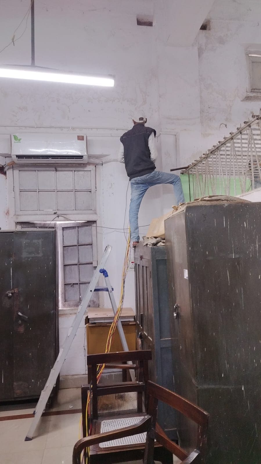 An electrician running riser cable at ceiling level inside a building