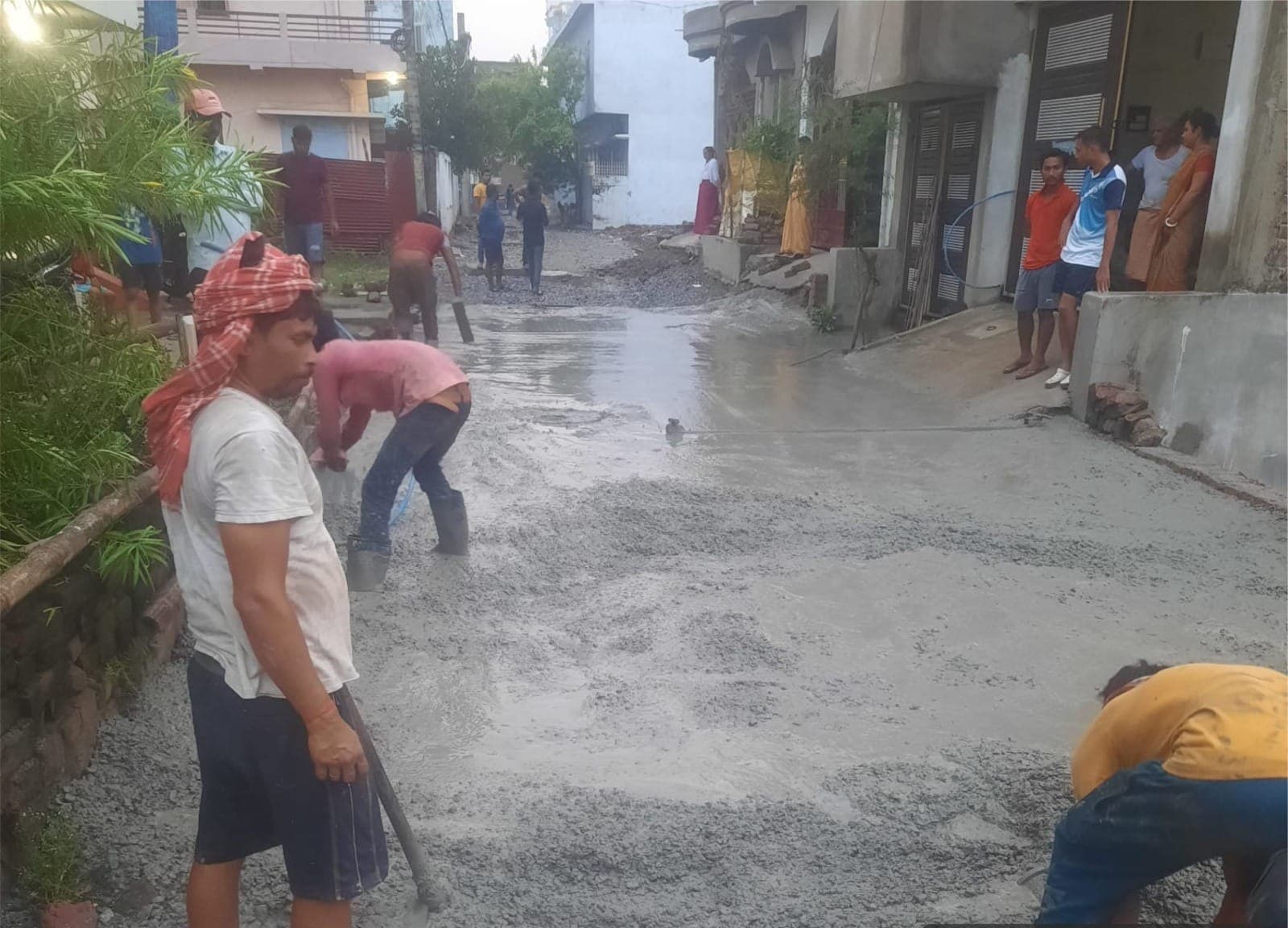 A crew placing and levelling a concrete road slab in a Patna colony
