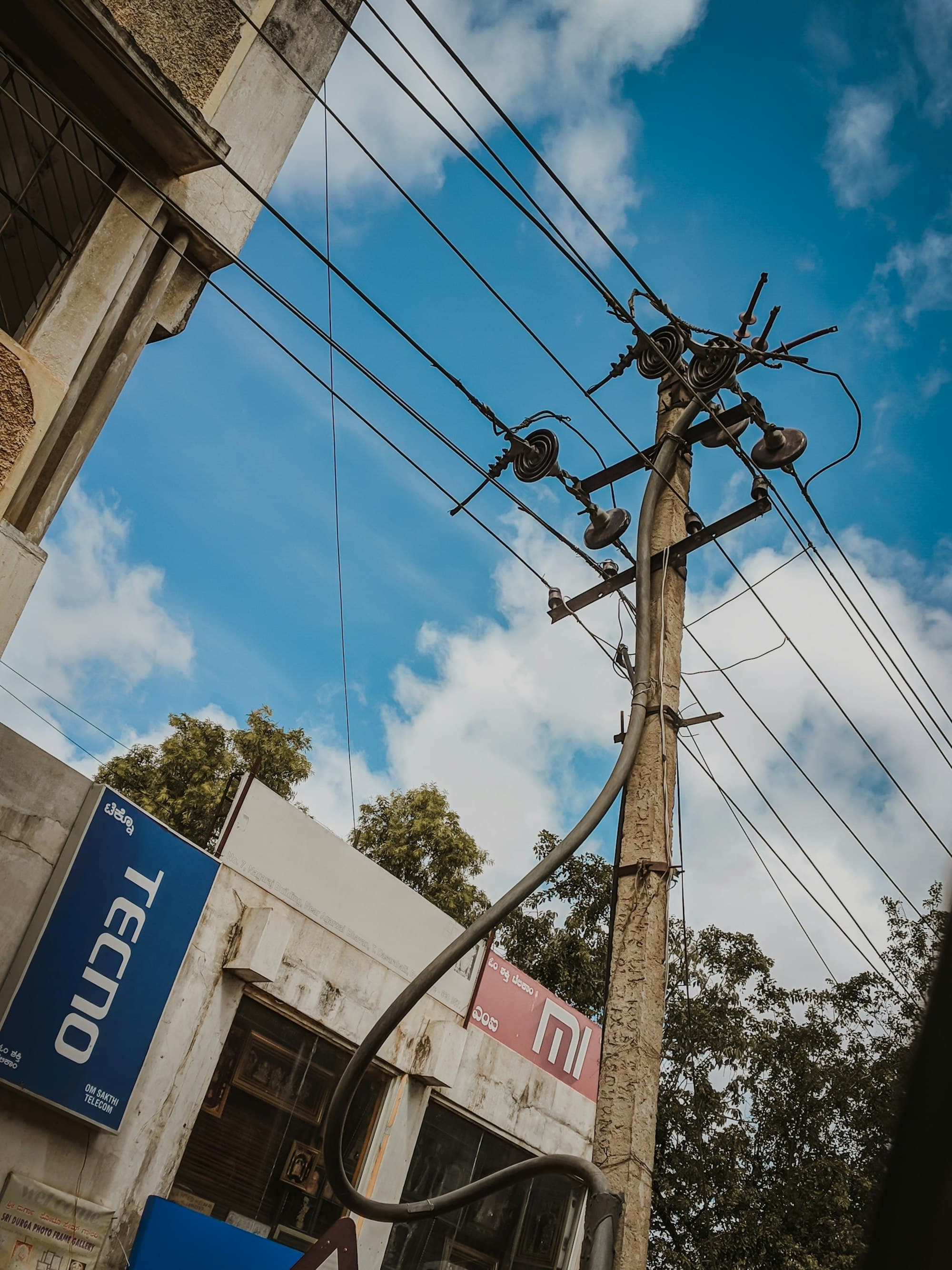 An overhead distribution pole carrying insulators, jumpers and service cables against a blue sky